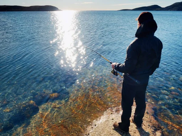 Balıkçı onay satırı balıkçılık ve yem çubuk üzerinde bastırıyor. Gün batımında balıkçı siluet 