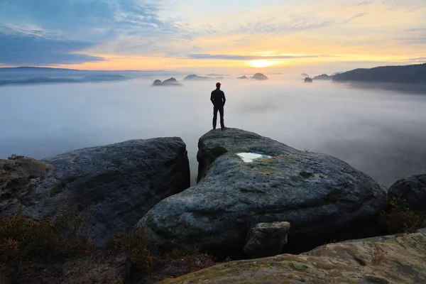 Wanderer am Felsenende über dem Tal. Mann wacht über nebeliges und herbstliches Morgental zur strahlenden Morgensonne. — Stockfoto