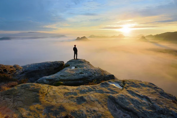 Wanderer am Felsenende über dem Tal. Mann wacht über nebeliges und herbstliches Morgental zur strahlenden Morgensonne. — Stockfoto