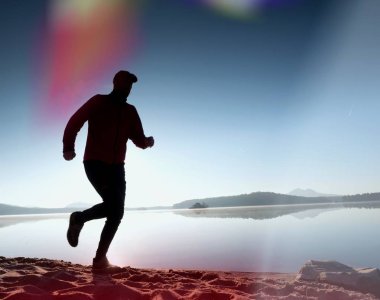 Kaçak ışık objektif. . Çalışan adam. Koş, sporcu adam kumlu bir plaj üzerinde gündoğumu sırasında koşu.