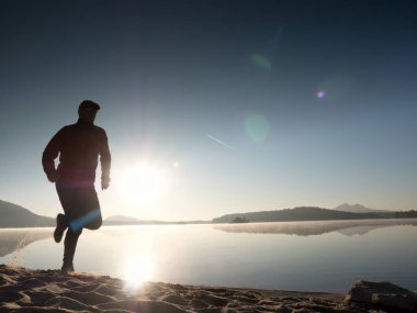 Uzun kumsalda hızlı deniz kıyısında koşan adam uygun. Güçlü runner yaz sabah açık eğitim.