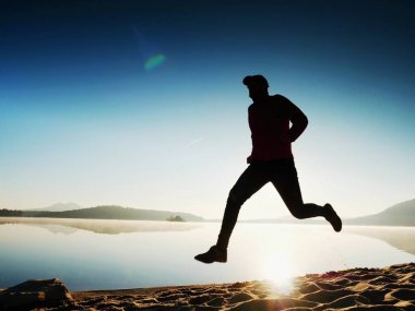 Uzun kumsalda hızlı deniz kıyısında koşan adam uygun. Güçlü runner yaz sabah açık eğitim.