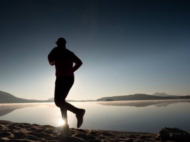 Uzun kumsalda hızlı deniz kıyısında koşan adam uygun. Güçlü runner yaz sabah açık eğitim.