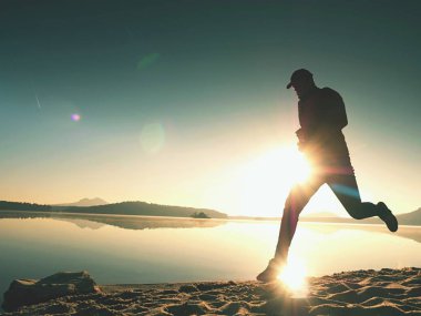 Uzun kumsalda hızlı deniz kıyısında koşan adam uygun. Güçlü runner yaz sabah açık eğitim.