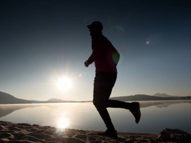 Gün doğumunda yansımayla plajda koşan bir çocuk. Açık gökyüzü ile Sabah Koyu Sahili.