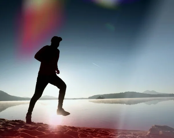 Hombre haciendo ejercicio y estirándose en la playa del lago al amanecer. Estilo de vida saludable. Solo joven fitness hombre ejercicio en la playa de la mañana — Foto de Stock