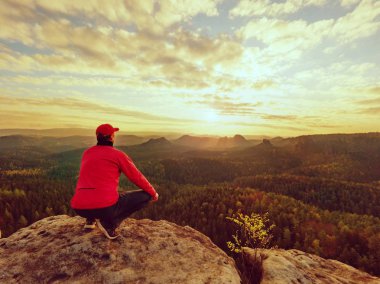 Uzun yürüyüşe çıkan kimse bir dağın tepesinde duran ve gündoğumu zevk. Güzel an 