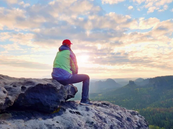 Sam turystycznych odpocząć. Turysta w zielony czarna kurtka siedzi na skalisty szczyt — Zdjęcie stockowe