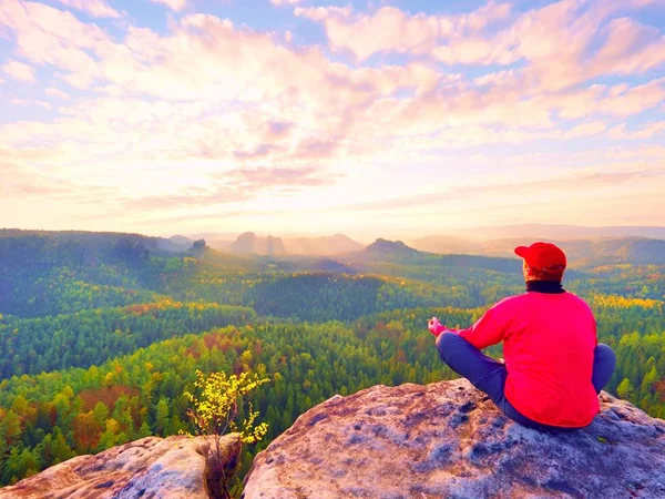 Alleenstaande man toeristische zitten op rock rijk. Uitkijkpunt met blootgestelde rotsachtige piek boven vallei. — Stockfoto