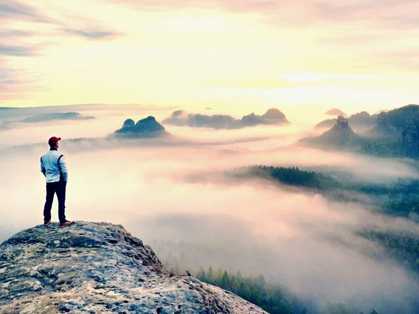 Einsamer Wanderer mit roter Mütze steht auf dem Gipfel des Sandsteinfelsens im Felsenimperium Park und wacht über den Nebel — Stockfoto