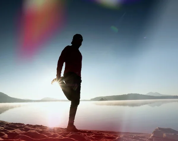 レンズの光の漏れ。山湖のビーチに行使する背の高いスリムな男. — ストック写真