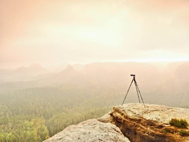 Tripod üzerinde tepe photogrpahy için hazır. Kayalık bakış maruz. Puslu yağmurlu sonbahar gün