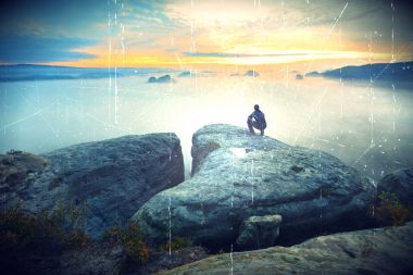  Uzun yürüyüşe çıkan kimse rock ve renkli sis ve sis izlerken tepe üzerinde çömelme pozisyonda