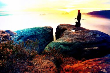 Arka adam siluet kayalık tepe üzerinde keskin. Uzun yürüyüşe çıkan kimse tatmin manzarasının tadını çıkarın. Kayalık uçurum yatay olarak aşağı izlerken üzerinde uzun boylu adam. 