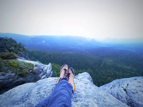 Detalhe das pernas de caminhante em botas de caminhada laranja preta no cume da montanha. Pés em sapatos de trekking — Fotografia de Stock