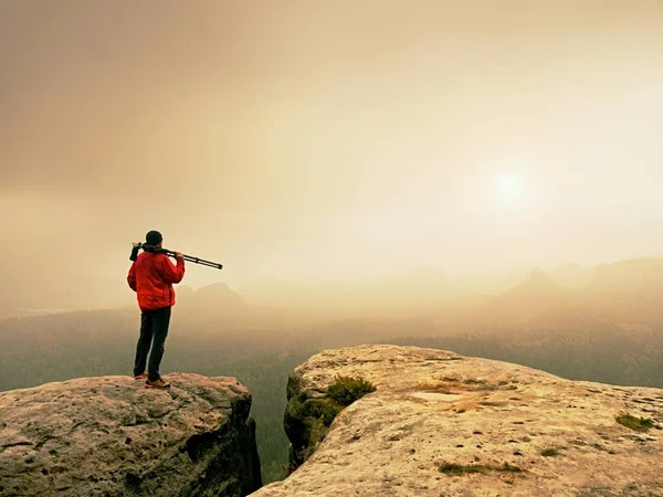 Sanat fotoğrafçısı yere tepe kaya üzerinde kamera ile fotoğraf çeker. Sisli manzara