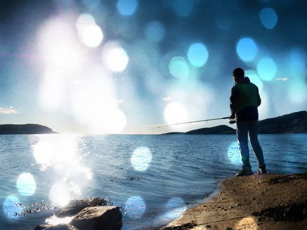 Etkin adam Denizi kayalık kıyıdan balık tutuyor. Balıkçı balıkçılık satırındaki iterek yem kontrol