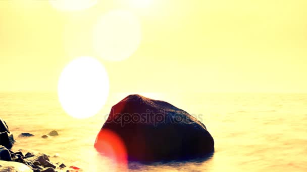 Defecto de la lente. Brillantes y brillantes olas marinas y rocas que sobresalen del agua en el crepúsculo. Puesta de sol rosa en la costa rocosa del mar Báltico . — Vídeos de Stock