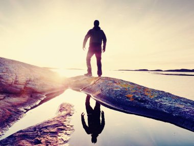 Siluet kişi yukarıda deniz cliff. Turist kaya üzerinde tek başına ve deniz ufuk izle