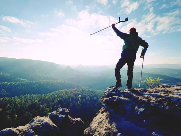 Turist med underarmen krycka ovanför huvudet på leden. Sårad hiker uppnåtts bergstopp — Stockfoto