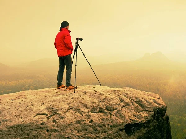 Fotógrafo de arte no local tira fotos com câmera no pico do rock. Paisagem nebulosa — Fotografia de Stock