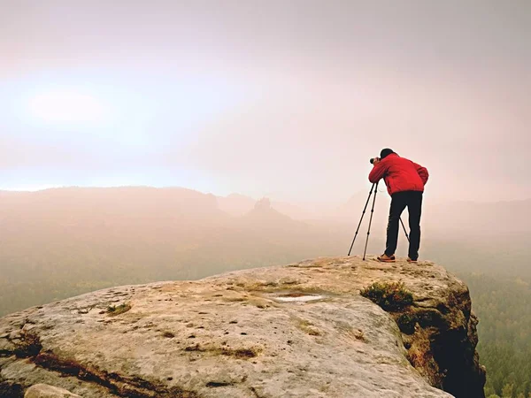 Professional photographer work on mountain peak. Nature photographer takes photos with mirror camera on rock