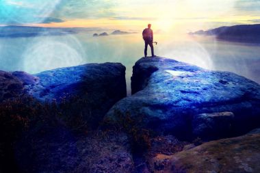 Arka adam siluet kayalık tepe üzerinde keskin. Uzun yürüyüşe çıkan kimse tatmin manzarasının tadını çıkarın. Kayalık uçurum yatay olarak aşağı izlerken üzerinde uzun boylu adam. 