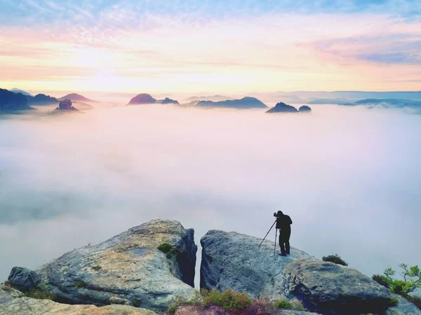 Professional na útesu. Příroda fotograf pořizuje fotografie s zrcadlový fotoaparát na vrcholu skály. Zasněný mlha — Stock fotografie