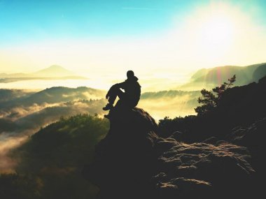Adam turist maruz kayanın üzerinde oturmak. Heather ve dalları ile bakış