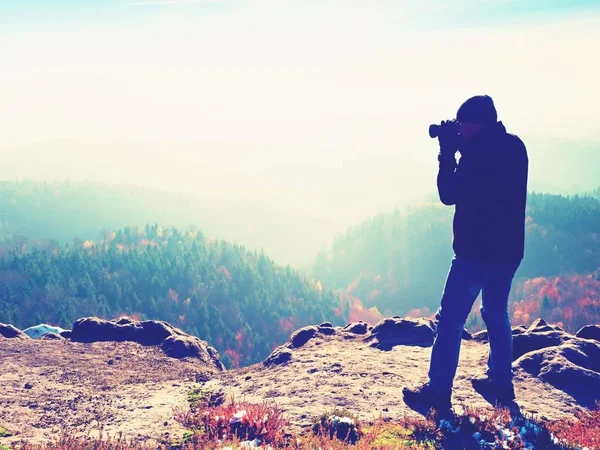 Photographer  on cliff. Nature photographer takes photos with mirror camera on peak