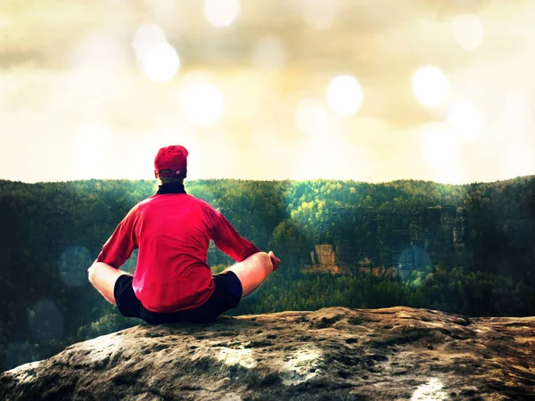 Homem sentado no topo da montanha em pose de ioga. Exercício de ioga na borda com uma vista deslumbrante — Fotografia de Stock