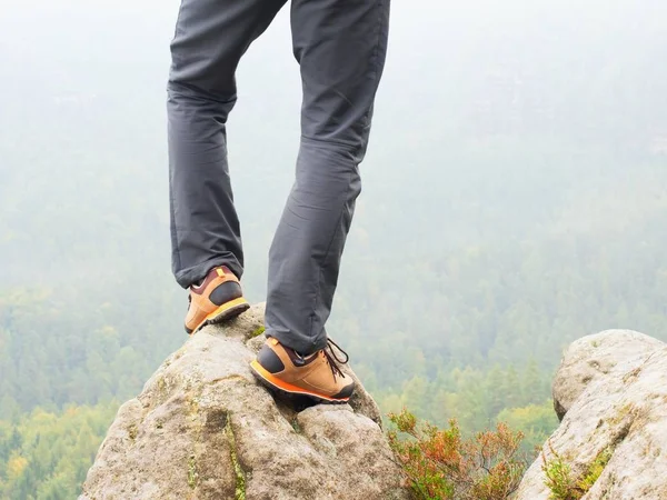 Hiker legs in comfortable trekking  boots on rock. Man legs in light outdoor trousers, leather shoes — Stock Photo, Image