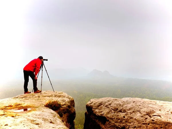 Fotógrafo olhando para visor do suporte de câmera digital dslr no tripé. Artista fotografando montanha e paisagem nublada — Fotografia de Stock