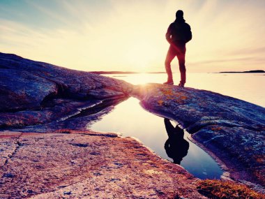 Fiyatı Polonyalılar ve sportif sırt çantası ile koyu spor giyim içinde. Kayalık sahil sahil şeridi iz. Yalnız turist keyfini çıkarın