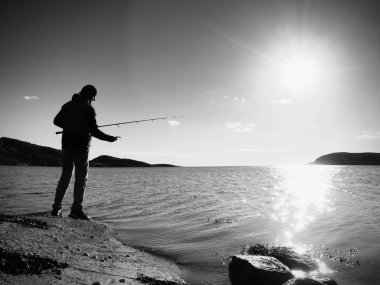 Etkin adam Denizi kayalık kıyıdan balık tutuyor. Balıkçı onay iterek yem 