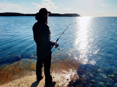 Etkin adam Denizi kayalık kıyıdan balık tutuyor. Balıkçı onay iterek yem 