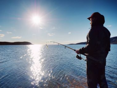 Etkin adam Denizi kayalık kıyıdan balık tutuyor. Balıkçı onay iterek yem 