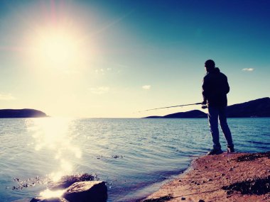 Etkin adam Denizi kayalık kıyıdan balık tutuyor. Balıkçı onay iterek yem 