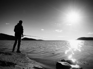 Etkin adam Denizi kayalık kıyıdan balık tutuyor. Balıkçı onay iterek yem 