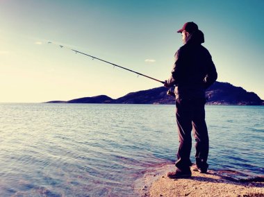 Balıkçı onay satırı balıkçılık ve yem çubuk üzerinde bastırıyor. Gün batımında balıkçı siluet 