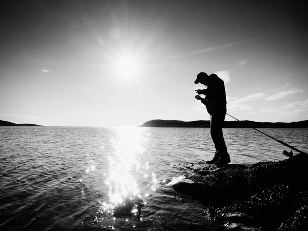 働く漁師に非常に近いリアビュー。男押す餌をチェックし、海にスローされます。. — ストック写真