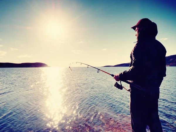 Fischer überprüfen Angelschnur und schieben Köder auf die Angel. Fischer Silhouette bei Sonnenuntergang — Stockfoto