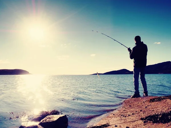 Pescador verificar linha de pesca e empurrando isca na haste. Silhueta de pescador ao pôr-do-sol — Fotografia de Stock
