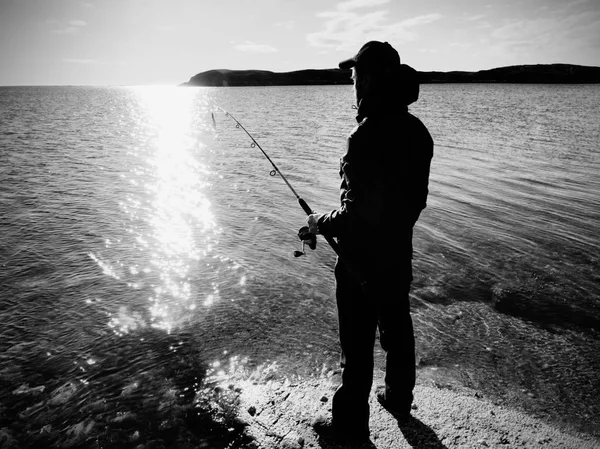 Şafakta iplik atan bir balıkçı silüeti. Etkin adam denizde Balık tutma — Stok fotoğraf