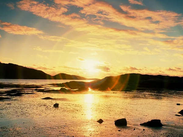 Spaziergang im Sonnenuntergang am Strand. Spiegelung des Sonnenuntergangshorizonts im Meerwasser zwischen Felsen — Stockfoto