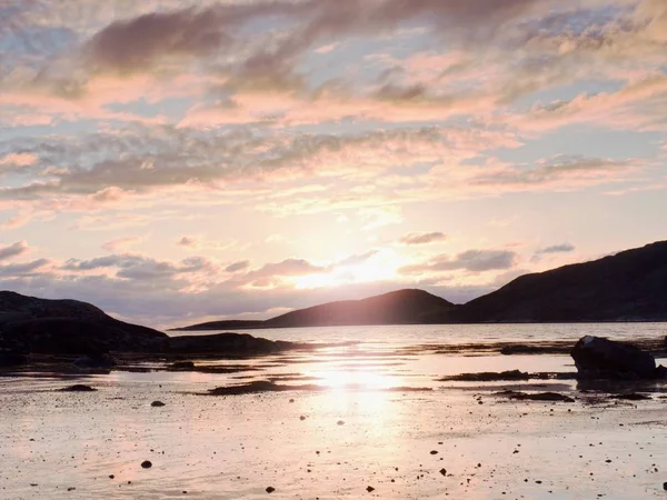 Caminar al atardecer en la playa. Espejo del horizonte de puesta de sol en el agua de mar entre las rocas — Foto de Stock