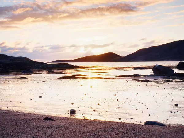 Günbatımı içinde sahilde yürümek. Deniz suyu kayalar arasında batışı ufukta, yansıtma — Stok fotoğraf