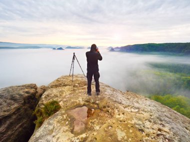 Fiyatı siyah kayalık tepe üzerinde. Harika daybreak dağlarda derin vadi ağır turuncu siste. 