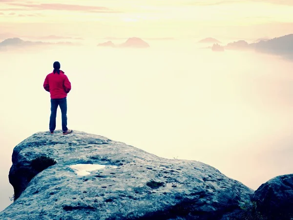 Escursionista uomo alla vetta della montagna. Splendido daybreak in autunno paesaggio nebbioso. Sole nascosto nelle nuvole — Foto Stock