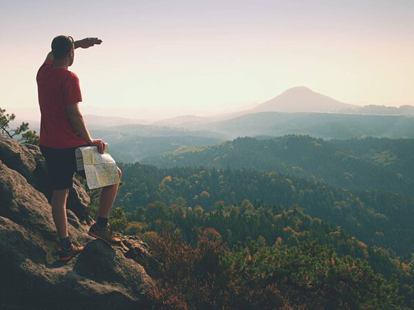 Спортивный человек стоит на горе с картой. Туристические путешествия пешком
,